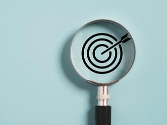 Magnifying glass looking at target and arrow